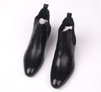 Pair of black leather Chelsea dress boots with elastic gore and rounded toe.