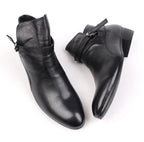 Black leather ankle boots with pointed toe and side buckle strap, low block heel.