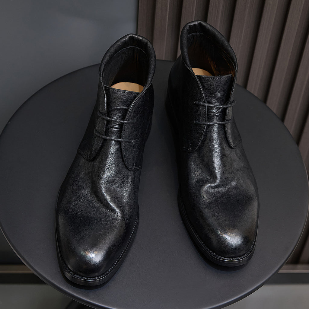 Black leather lace-up chukka boots pair, front-facing view with laces and tongue.