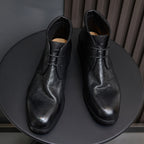 Black leather lace-up chukka boots pair, front-facing view with laces and tongue.