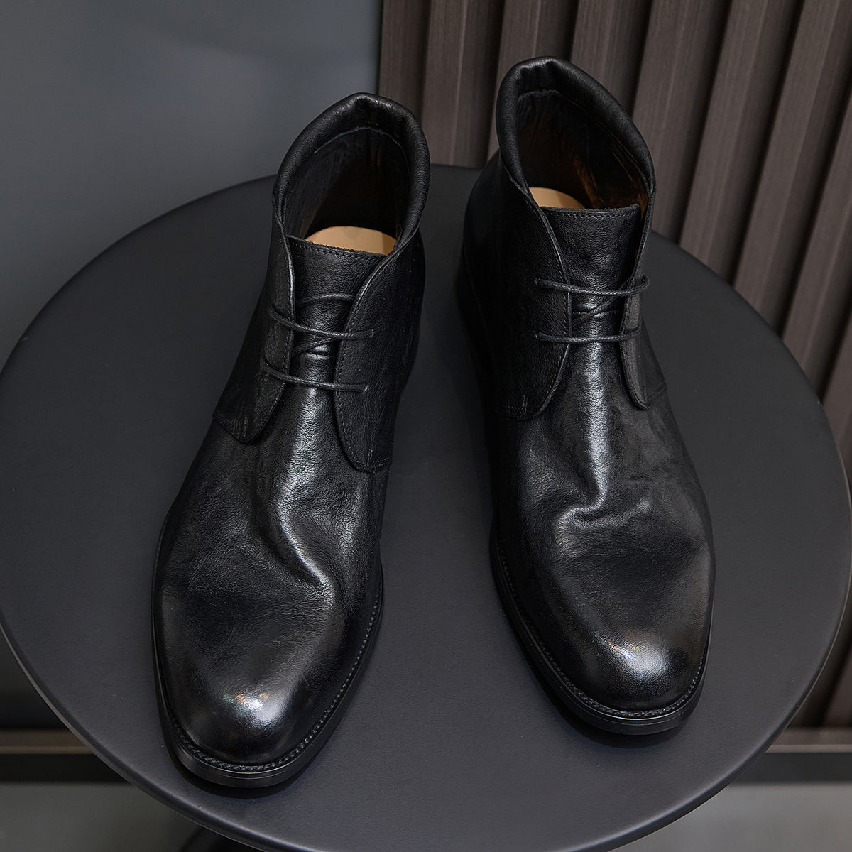 Black leather lace-up chukka boots pair, front-facing view with laces and tongue.