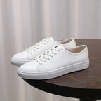 Men's leather sneakers, white low-top with lace-up front and rubber sole.
