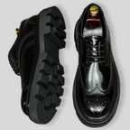 Lace-up pointed-toe leather derby shoes with perforated toe and treaded rubber outsole.