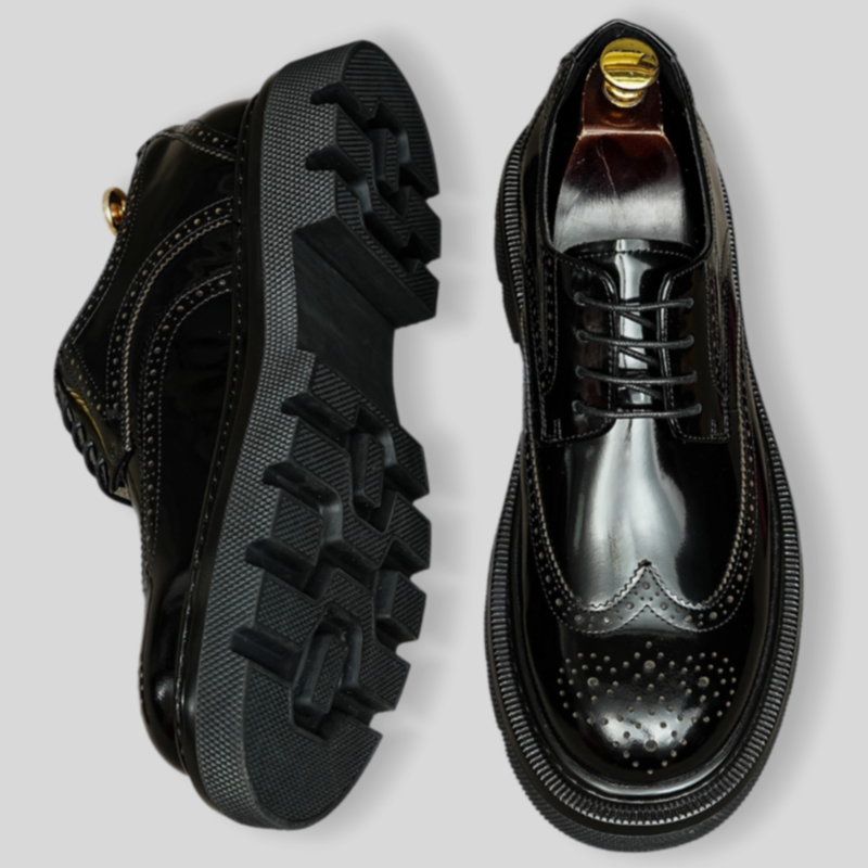 Lace-up pointed-toe leather derby shoes with perforated toe and treaded rubber outsole.