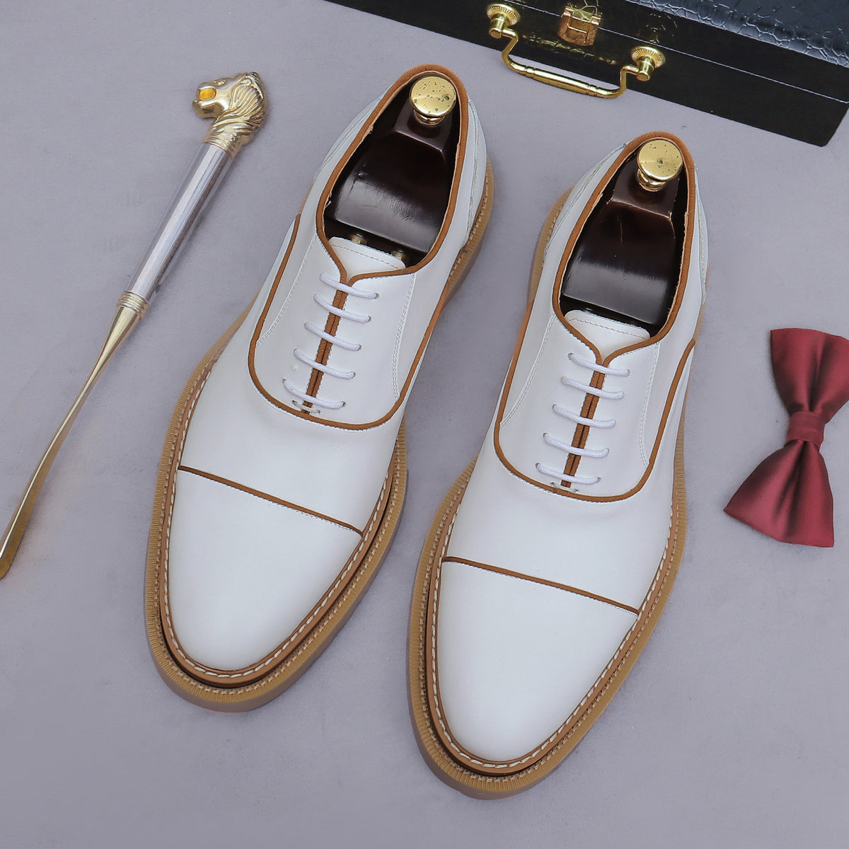 White lace-up oxford shoes with brogue/wingtip stitching and chunky lug sole, front view.