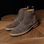 Men's dark gray suede chukka boots with lace-up front, brogue-style perforations, and sole
