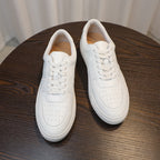 White men's leather sneakers, two pairs on table with lace-up vamps