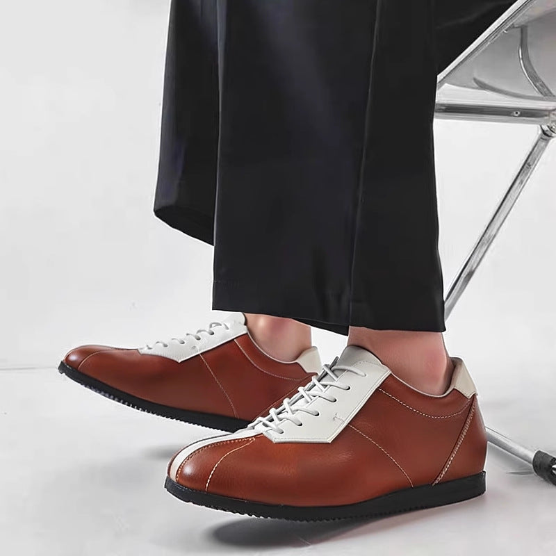Brown leather lace-up sneakers with white side panels and minimal curved stitching.