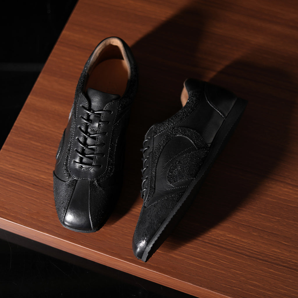 Men's black leather sneakers with lace-up closure and oval side patch detail