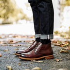 Dark brown leather lace-up chukka boots with plain toe, outdoor ground-level view.