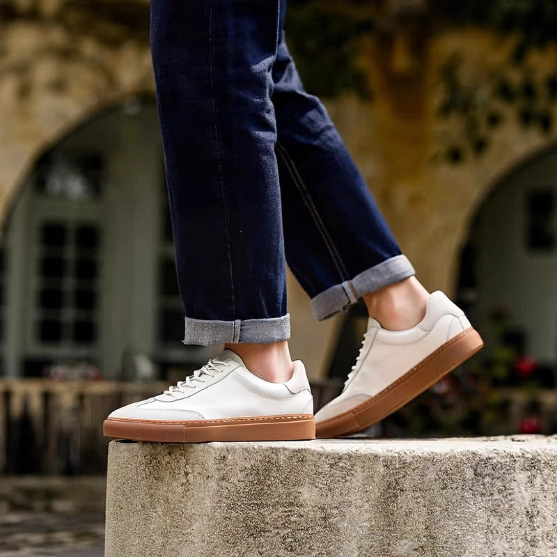 White leather sneakers on a ledge with tan sole and lace-up closure