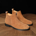 Tan suede ankle boots with pointed toe and side zipper, showing black outsole edge.