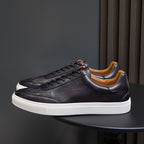 Men's leather sneakers, dark brown/black with white sole and tan interior.