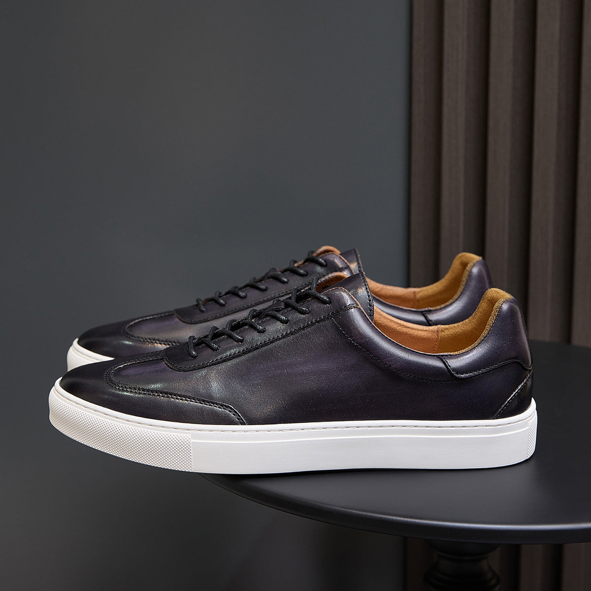 Men's leather sneakers, dark brown/black with white sole and tan interior.
