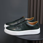 Leather sneakers, dark green lace-up with perforated toe and white rubber sole.