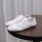 Men's white leather sneakers with lace-up front and padded collar on a table
