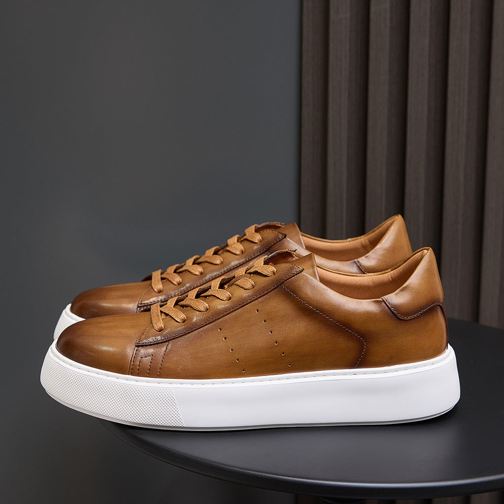 Men's tan-brown leather lace-up sneakers with white sole, perforation detail, and panel seams