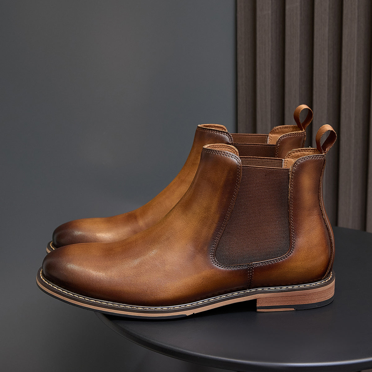 Side view of brown Chelsea dress boots with elastic gore, pull tabs, and stitched welt
