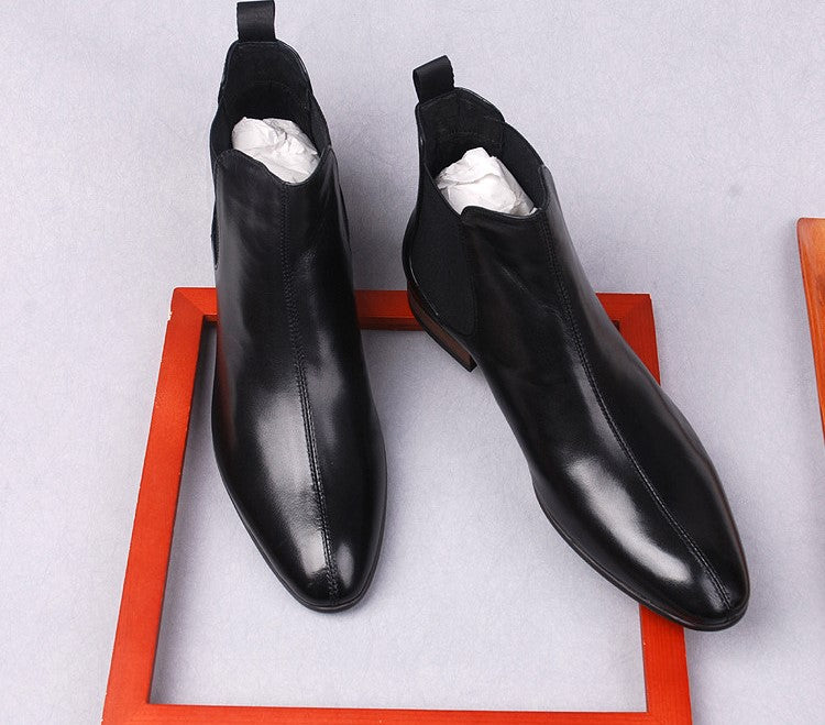 Black leather Chelsea boots viewed from above, showing elastic gore and rounded toe.