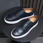Dark blue leather lace-up sneakers with white soles, shown from above angle