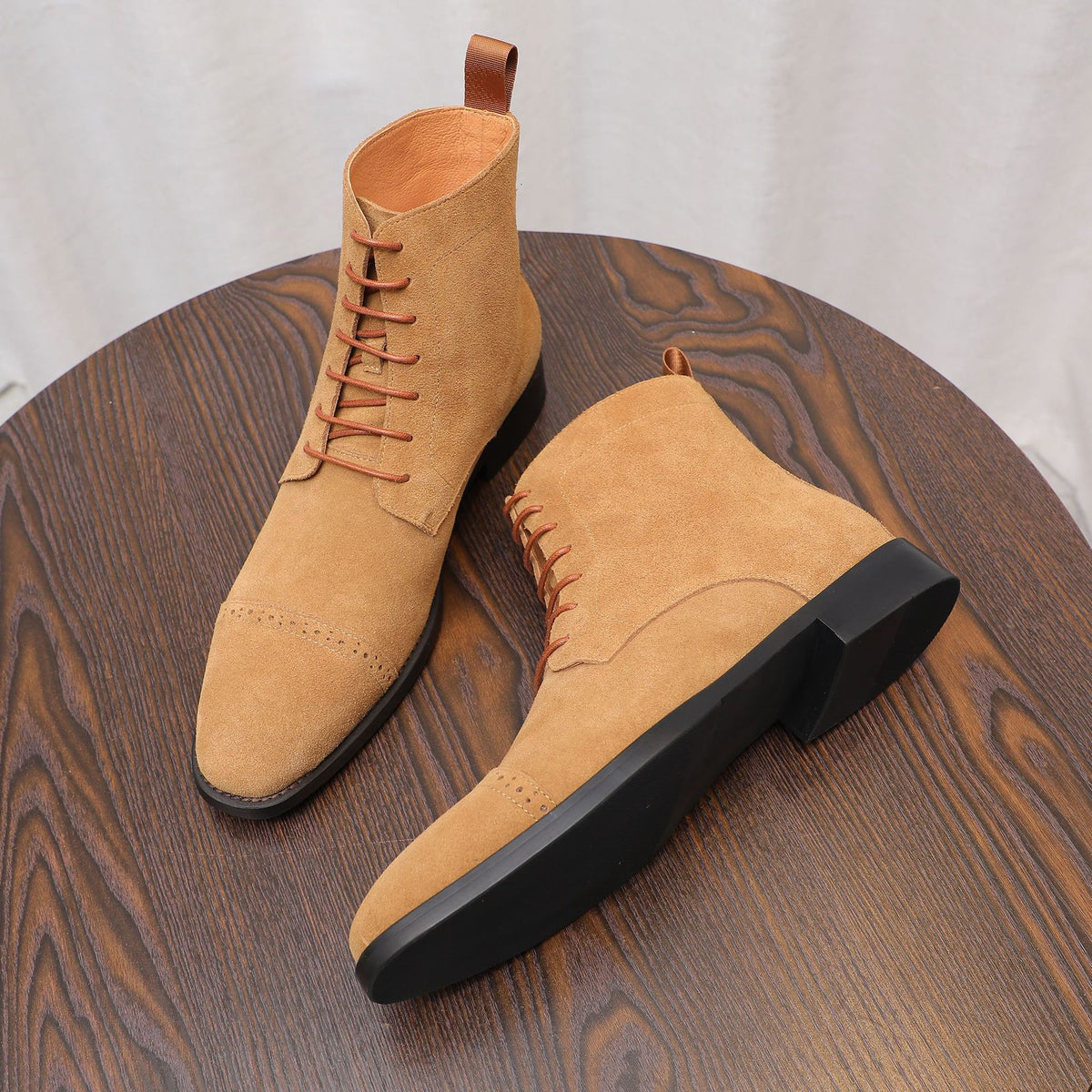 Tan suede lace-up chukka boots with plain toe and black rubber outsoles