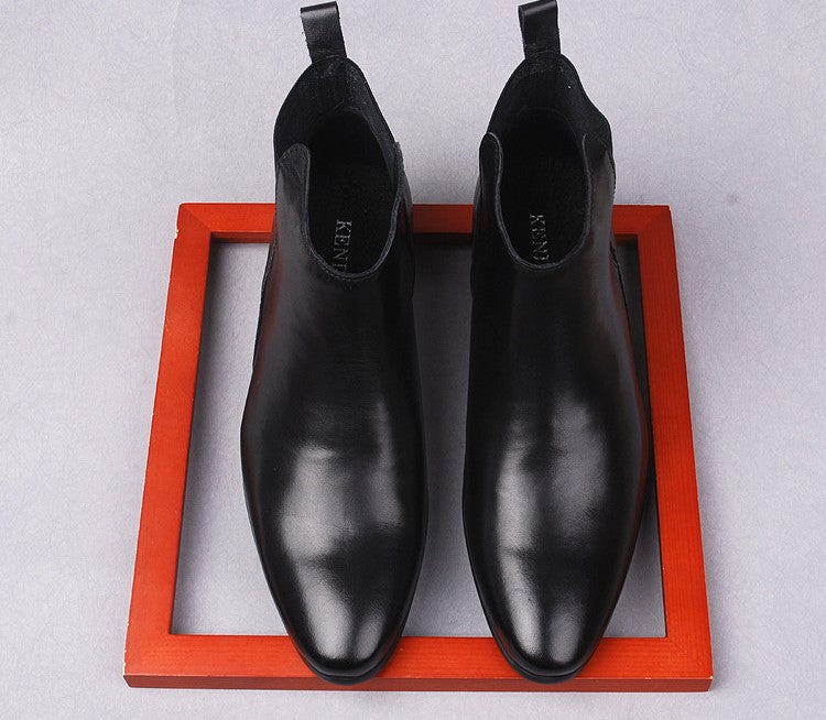 Black leather Chelsea boots with pull tabs and elastic gore on orange tray