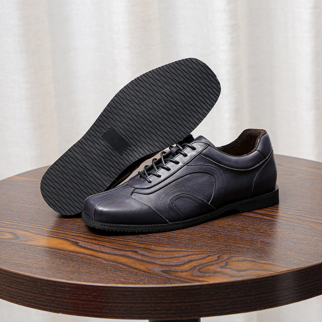 Men's dark gray leather sneakers with textured tread outsole and lace-up front