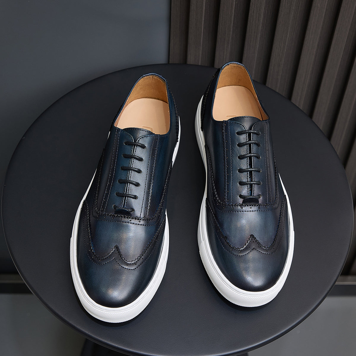 Dark blue leather lace-up sneakers, front view with white rubber soles