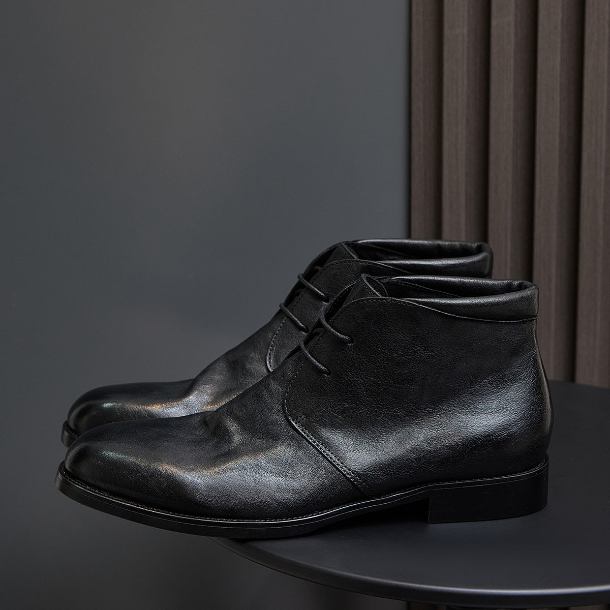 Black leather lace-up chukka boot, angled side view with lace-up vamp.