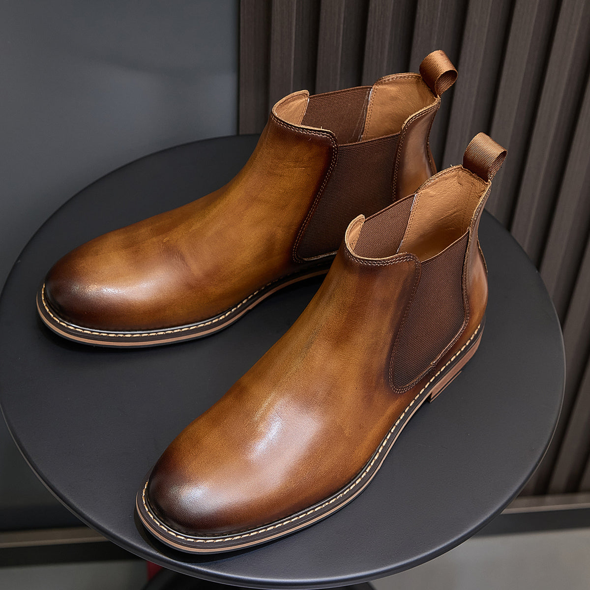 Two brown Chelsea dress boots with pointed toe, side elastic, and contrast stitched trim