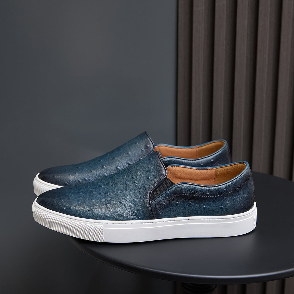 Men's blue slip-on leather sneakers with white sole, side details, and textured upper