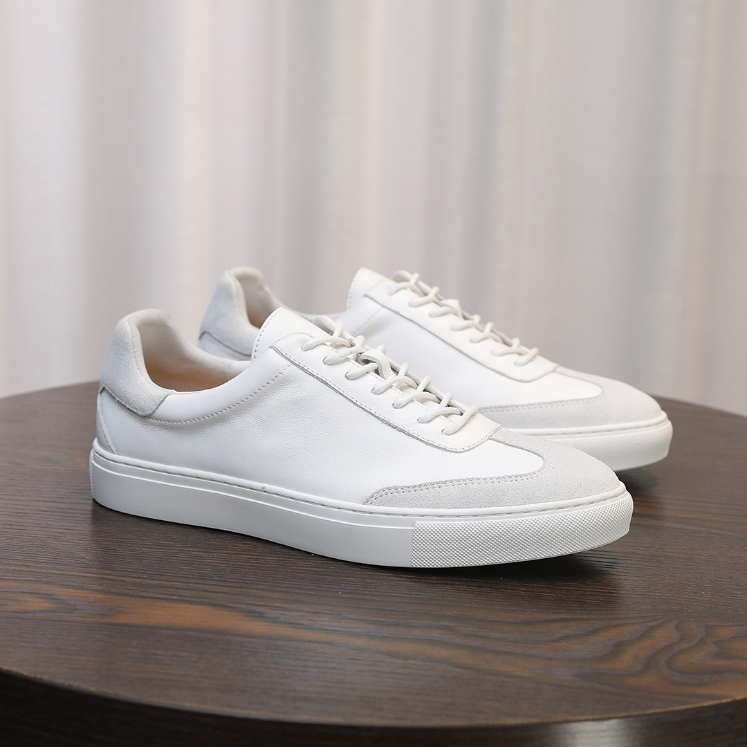 Men's white leather lace-up sneakers on a round wooden surface, minimalist design