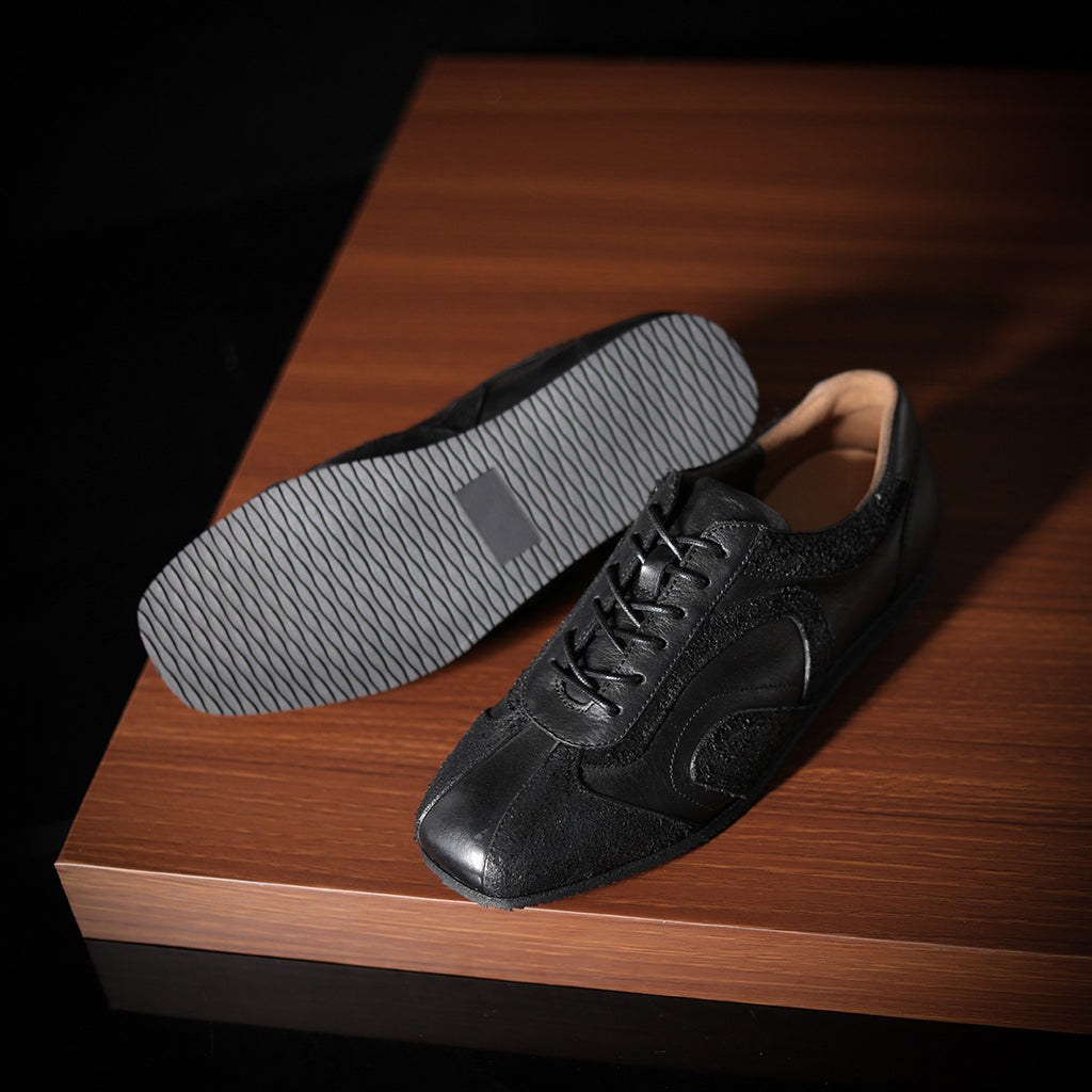 Men's black leather sneakers showing treaded outsole and lace-up upper