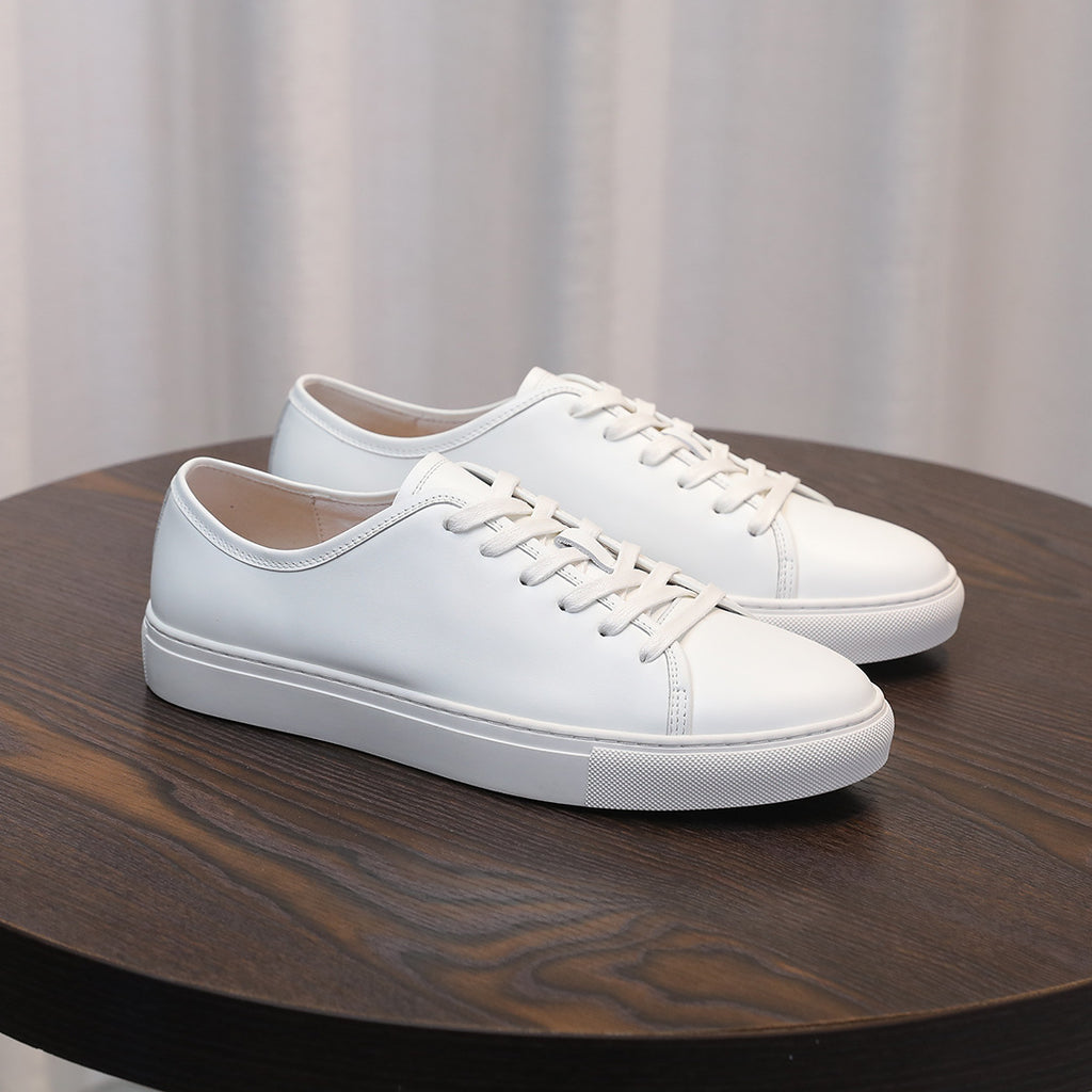 Men's leather sneakers, white low-top with lace-up closure and cushioned sole.