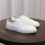 Men's leather sneakers, white low-top with lace-up closure and cushioned sole.