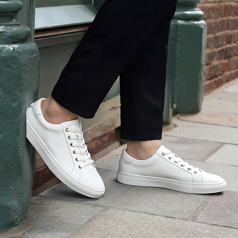 Men's white leather lace-up sneakers worn with dark pants, low-profile rubber sole