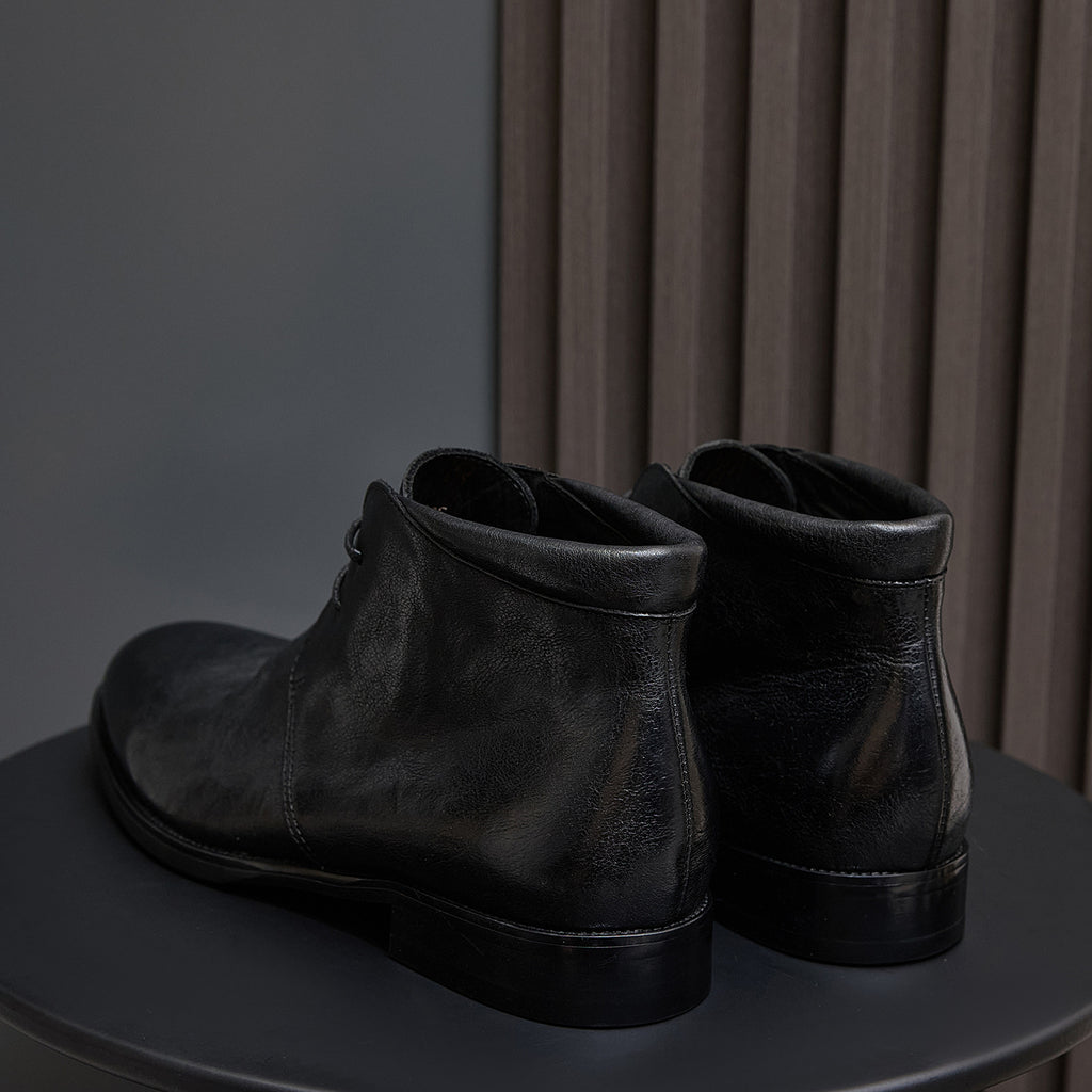 Black leather lace-up chukka boots, rear view with pull tab and heel.