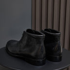 Black leather lace-up chukka boots, rear view with pull tab and heel.