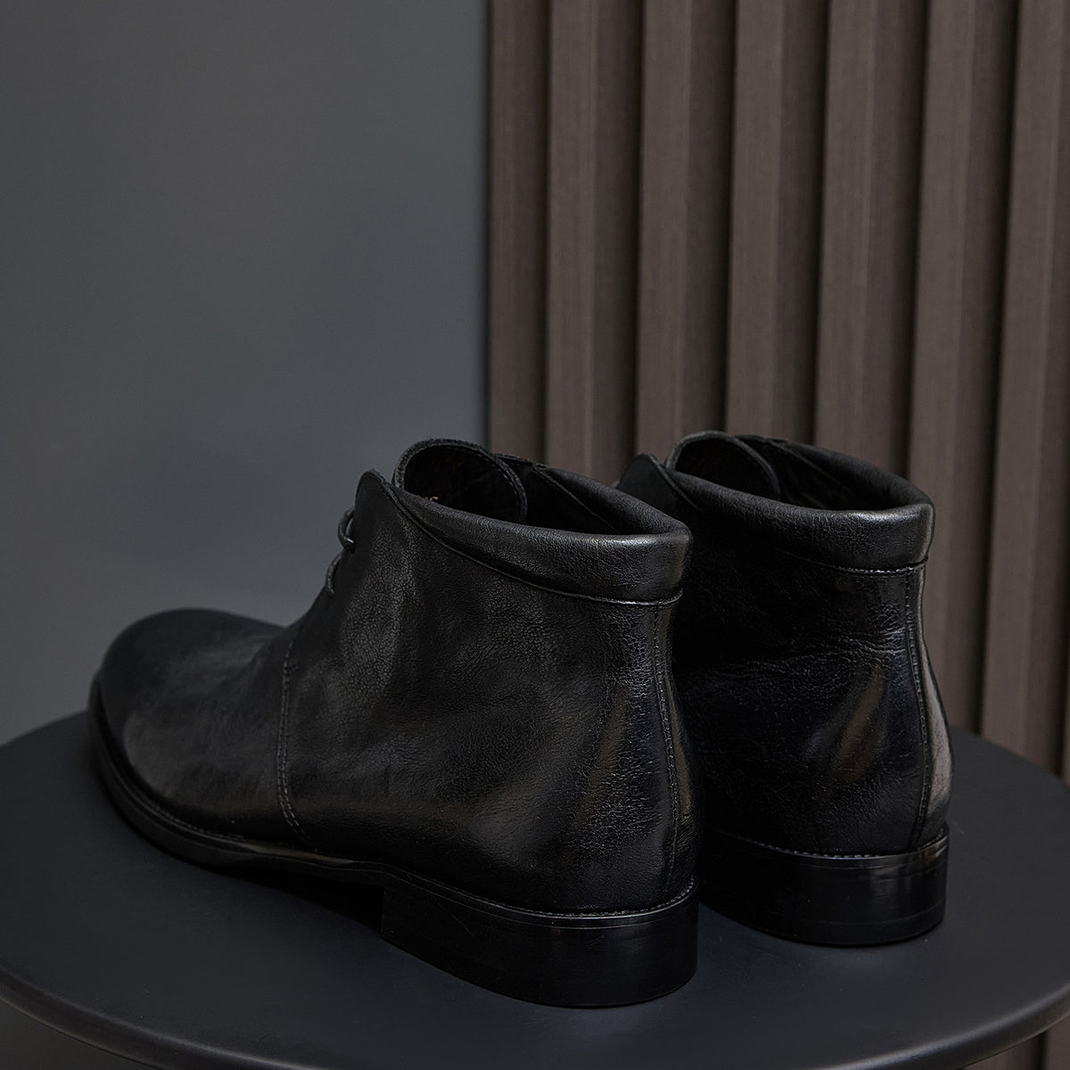 Black leather lace-up chukka boots, rear view with pull tab and heel.