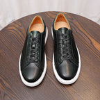 Pair of men's dark leather low-top sneakers with black laces and white midsoles