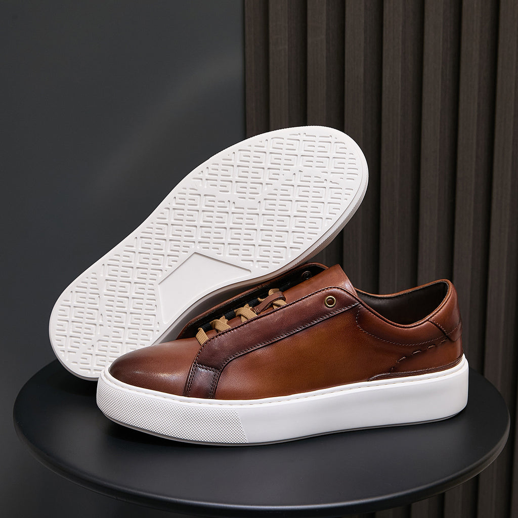 Men's brown leather sneakers showing white outsole tread and low-profile sole