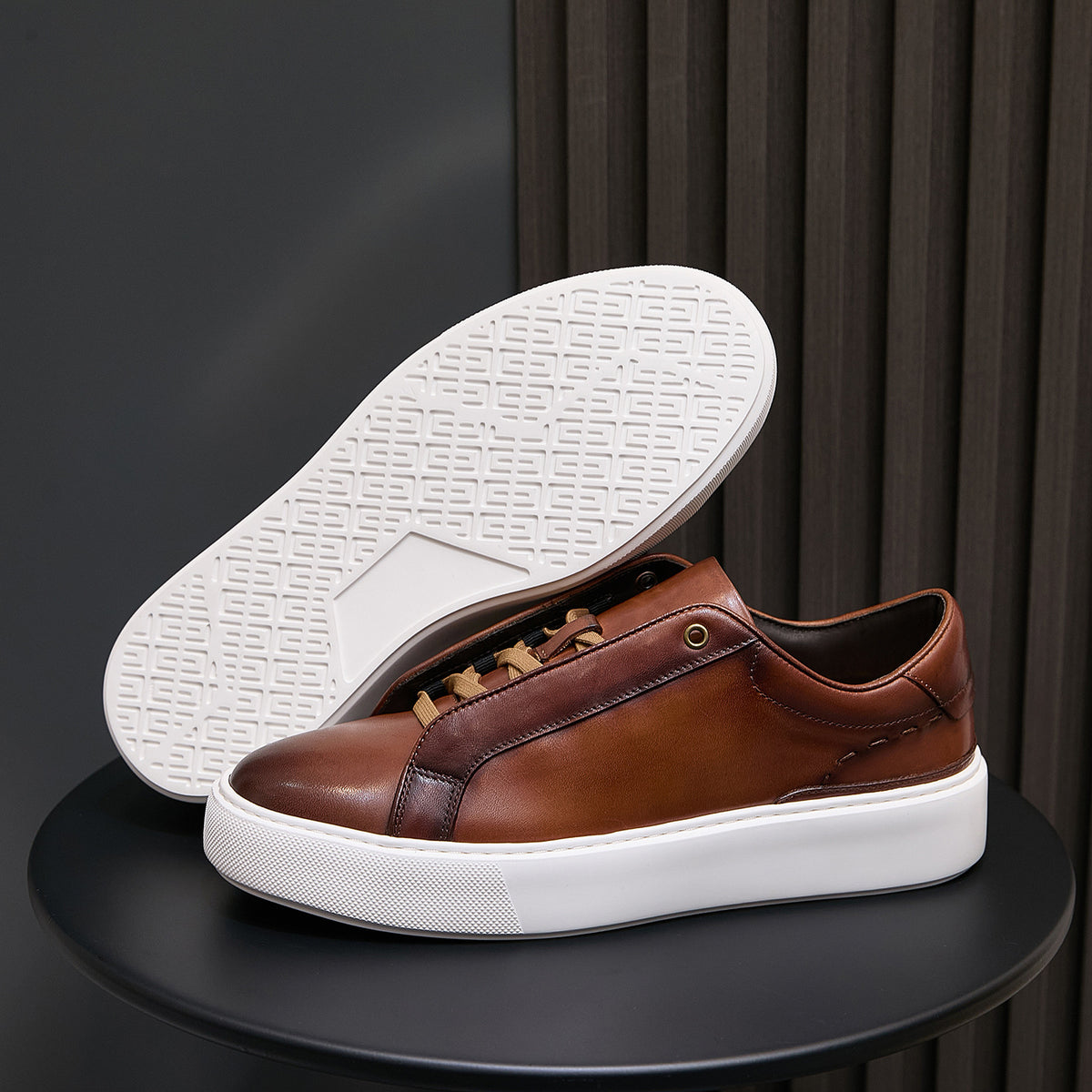 Men's brown leather sneakers showing white outsole tread and low-profile sole