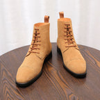 Tan suede lace-up chukka boots with brown laces and black rubber soles