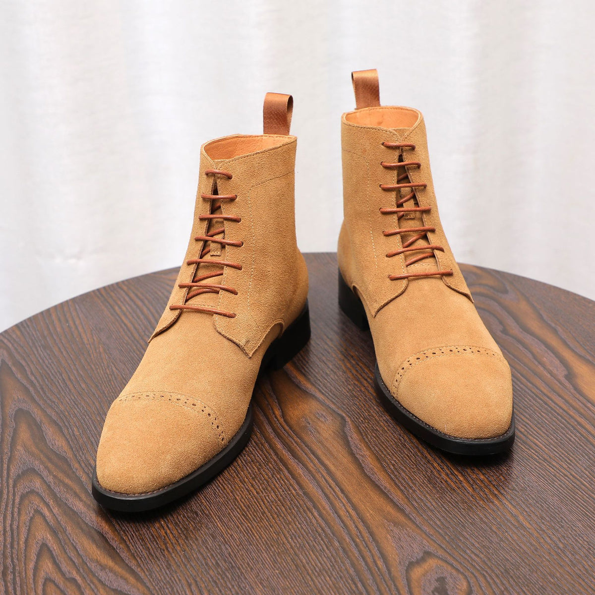 Tan suede lace-up chukka boots with brown laces and black rubber soles