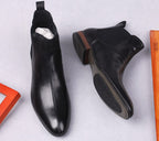 Black leather Chelsea boots with low block heel and dark rubber outsole.