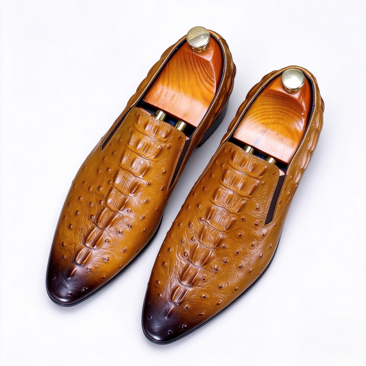 Men's brown exotic leather loafers with crocodile and ostrich skin textures, displaying luxury dress shoes with wooden shoe trees.
